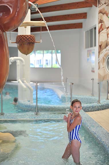 Fillette sous un jet d'eau dans la piscine couverte du camping près de Saint-Gilles-Croix-de-Vie
