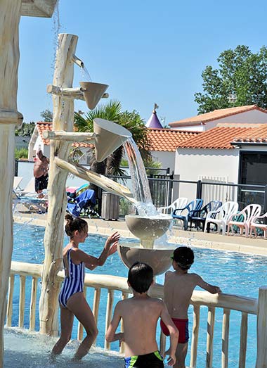 Enfants jouant sous les jets d'eau en forme d'arbre au camping Les Écureuils en Vendée