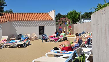 Plage et transats au bord de la piscine du camping Les Écureuils en Vendée
